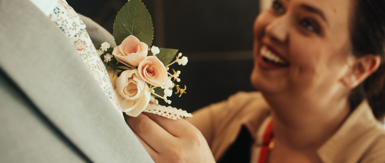 Woman putting boutonniere on groom.