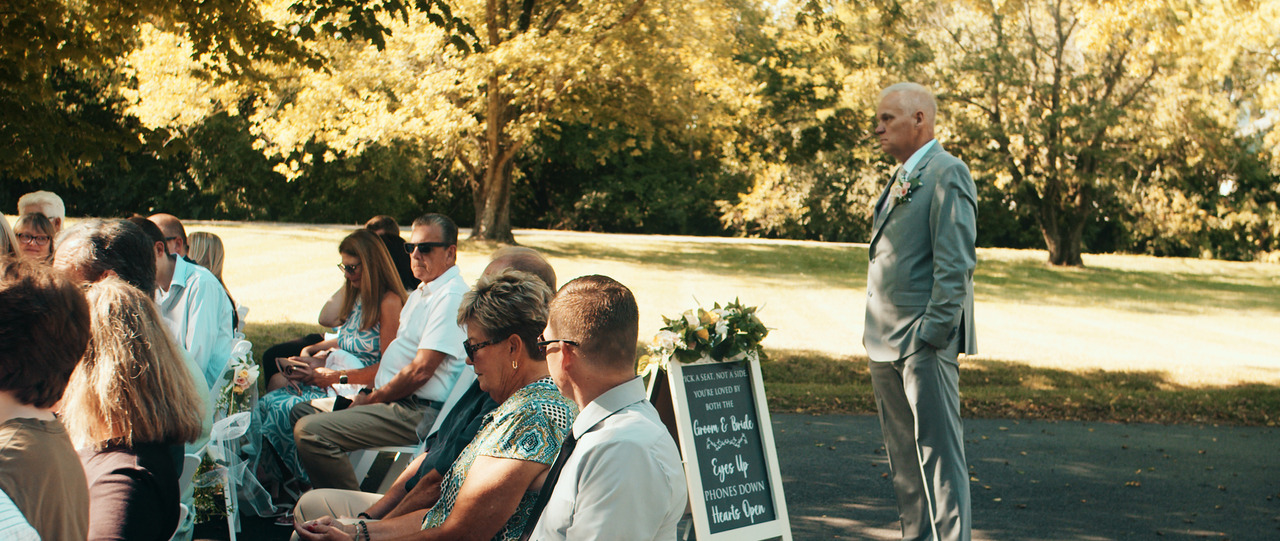 Groom standaing at stard of wedding aisle side view.