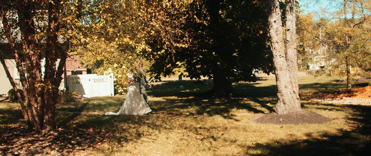 Bride and groom walking down forest path together.