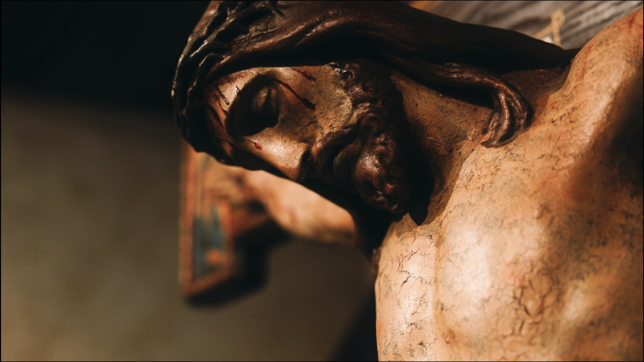 Closup of Jesus's face on wooden cruxifix.