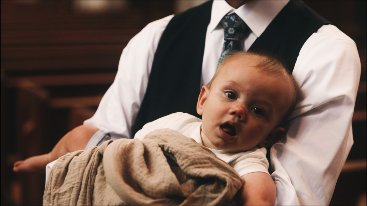 Man holding baby, baby is looking at camera with mouth open.