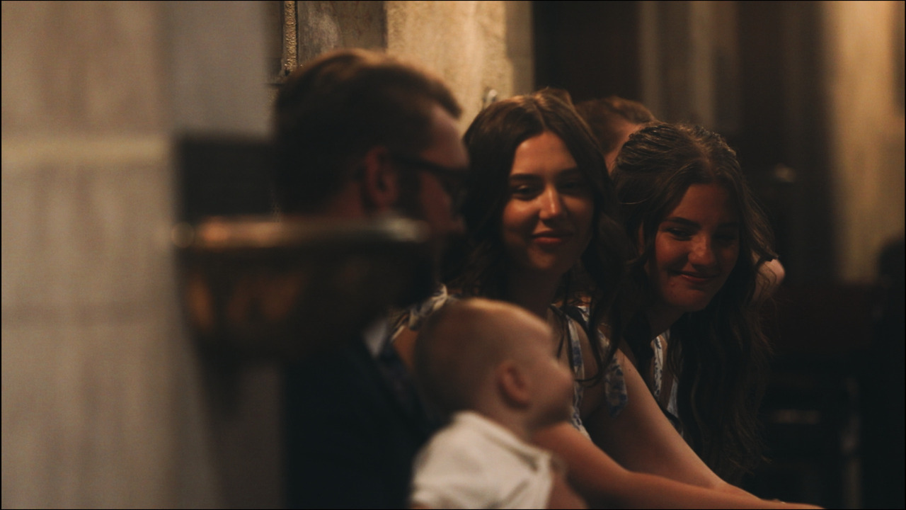 Bridesmaids fawning over the baby being held by man.