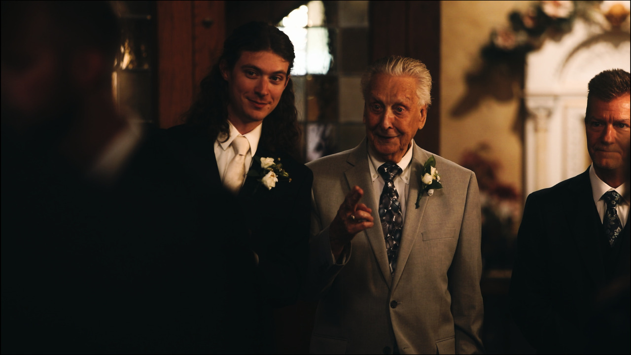 Groom with older man, looking at someone off-frame.