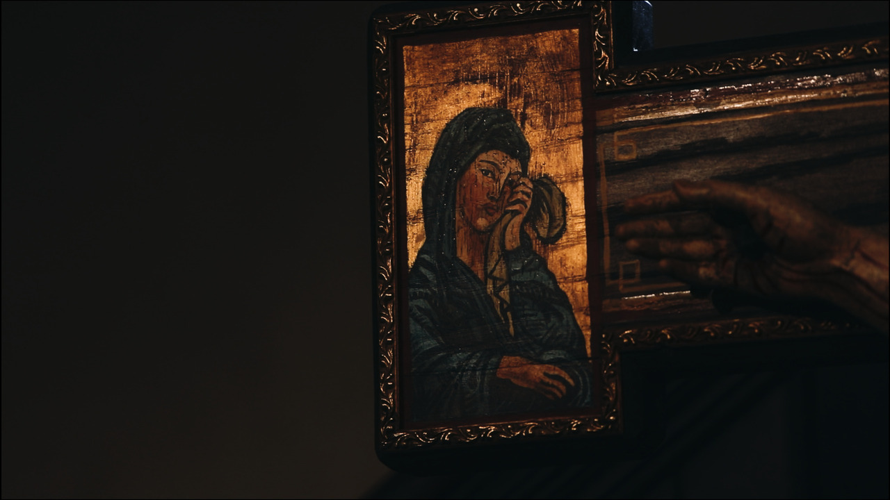 Icon of Virgin Mary weeping on right hand of wooden crucifix.