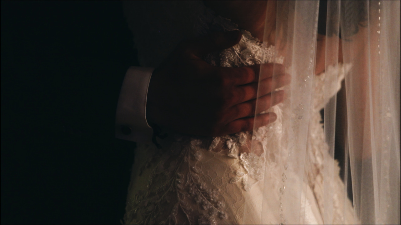 Closeup of groom's hand on bride's hip during first dance.