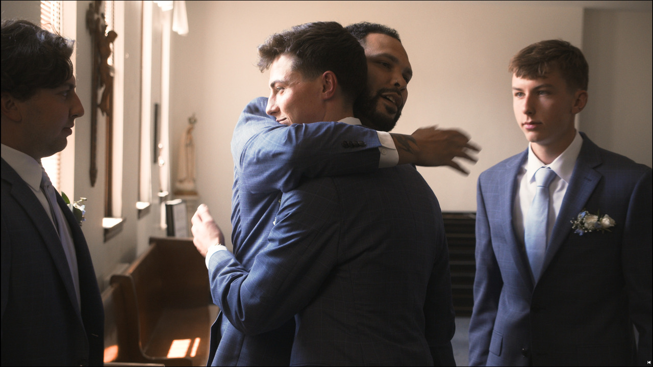 Groom hugs groomsman.