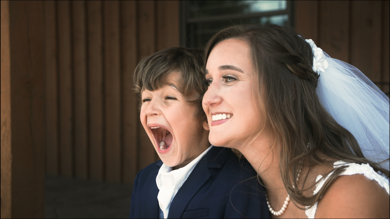 Bride gets photo taken with boy, boy makes silly face.