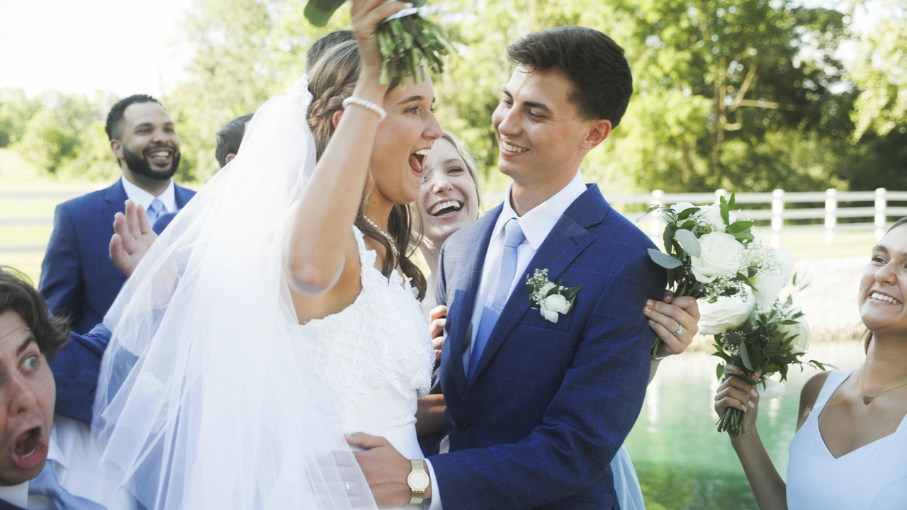 Bride and groom laugh and smile while bridal party makes silly faces around them.