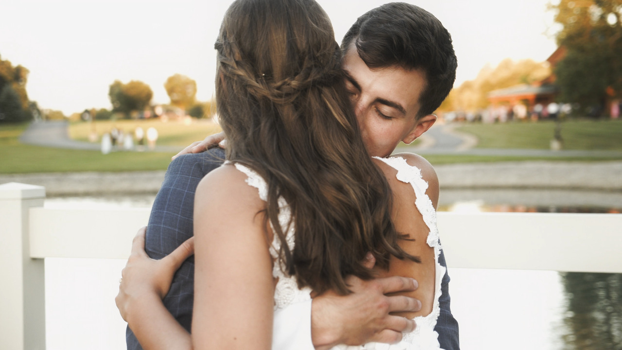 Groom nuzzles bride during hug.