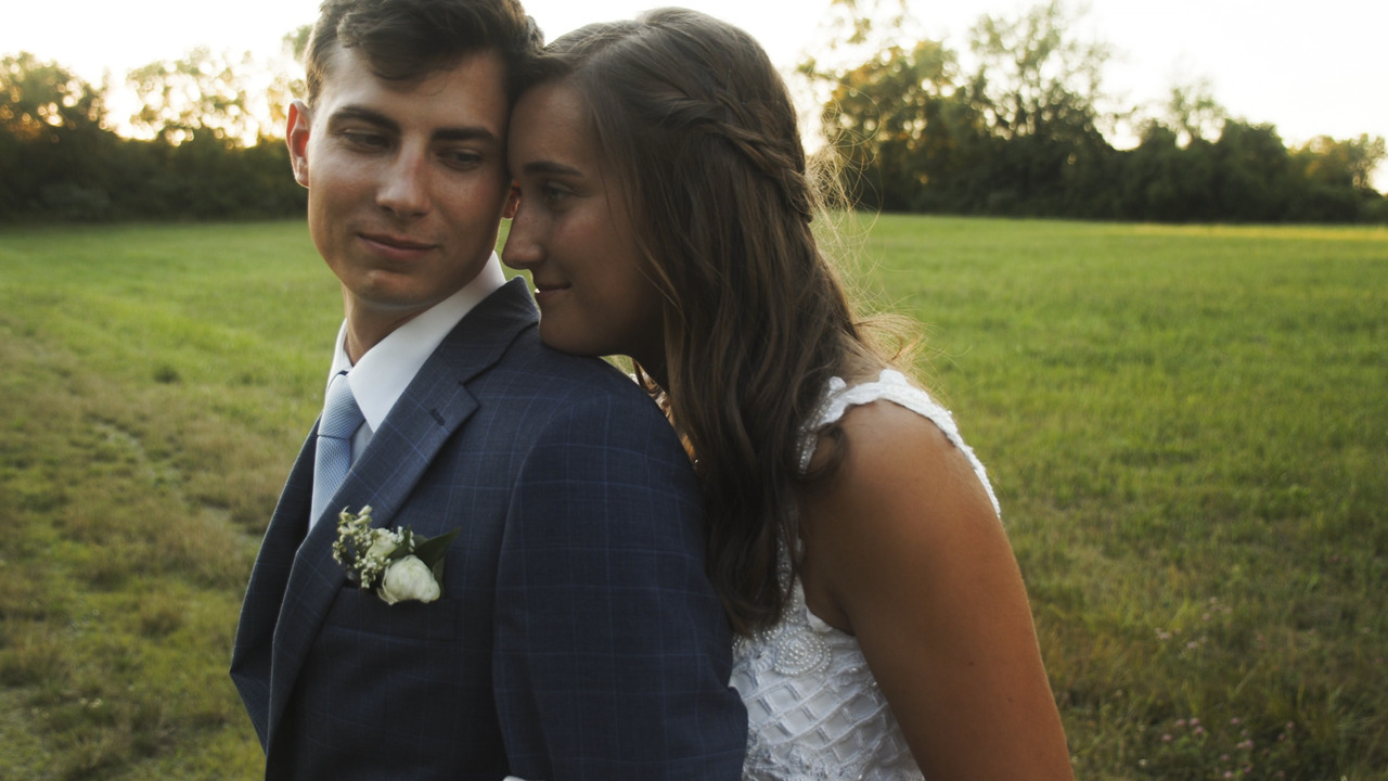 Bride rests her head on groom's shoulder from behind.