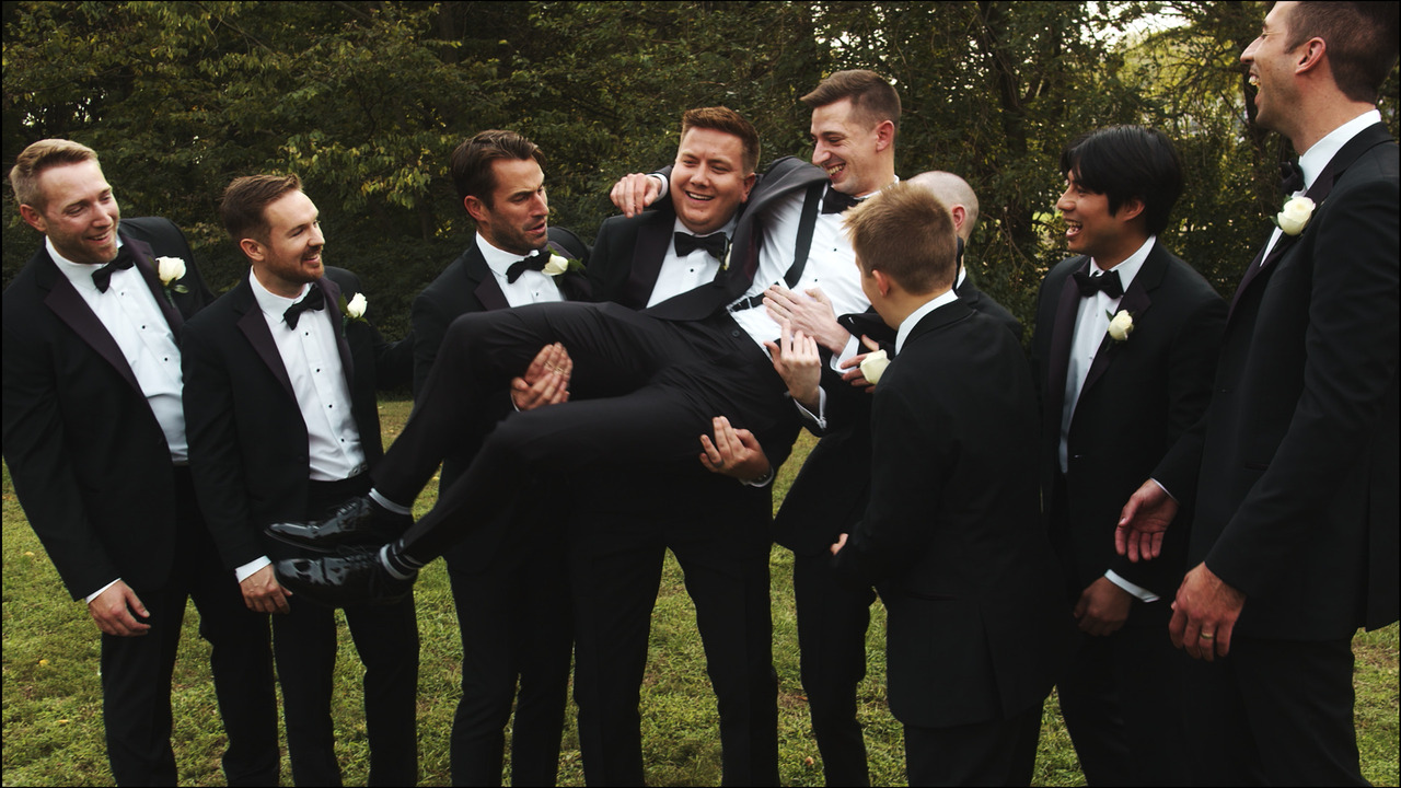 Groomsmen pick groom up and carry him.