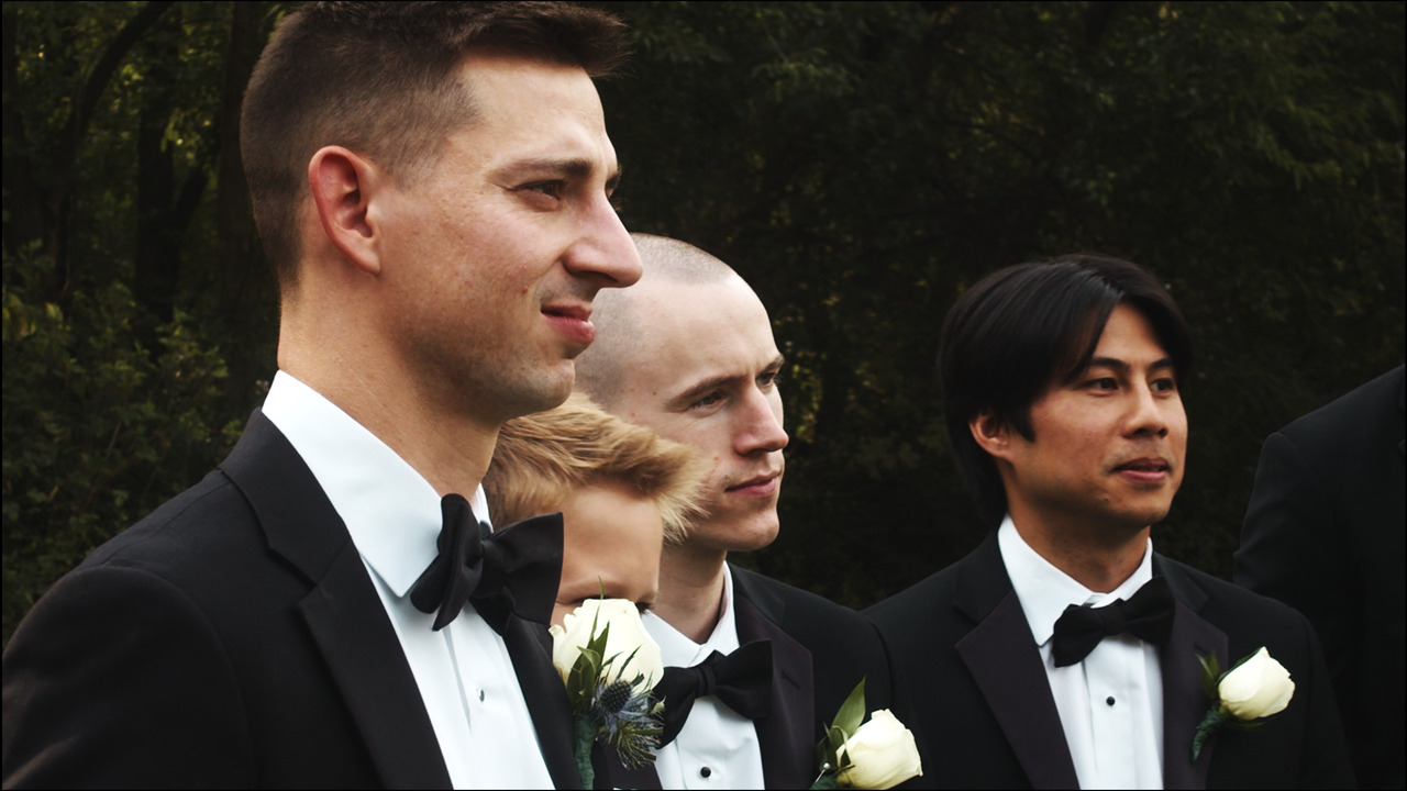Groom smirks while getting photo taken with groomsmen.