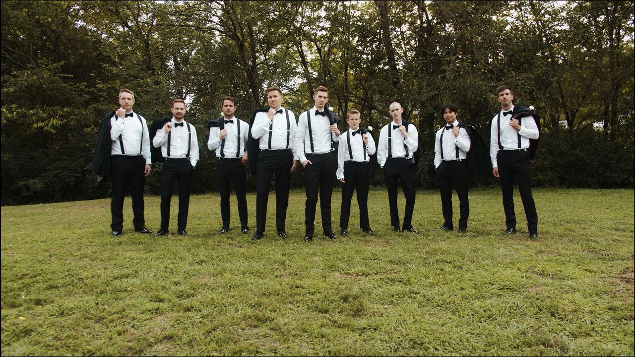 Groomsmen and groom take their jackets off for group photo.