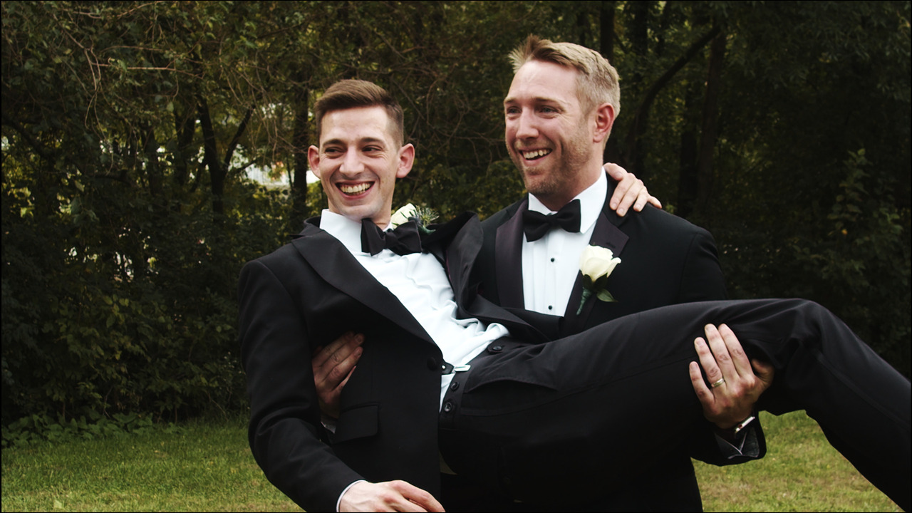 Groomsman picks groom up for individual photo.