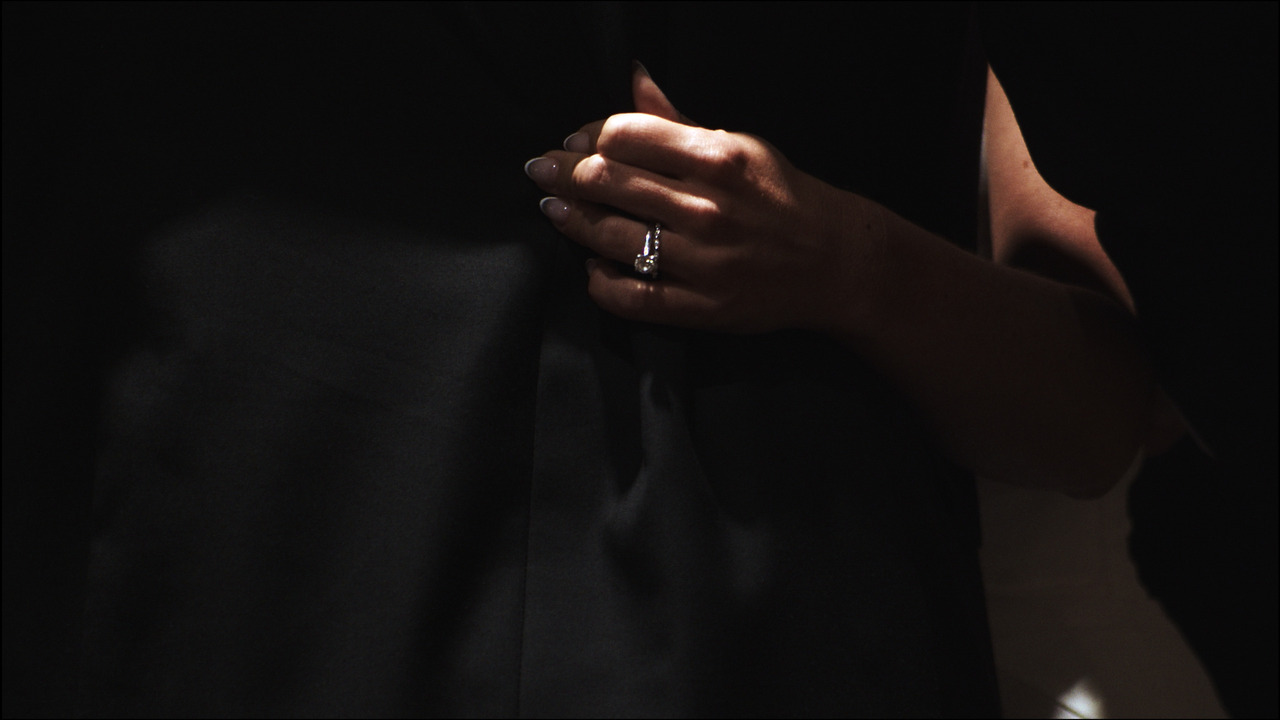 Closeup of bride's hand with wedding band and engagement ring during first dance.