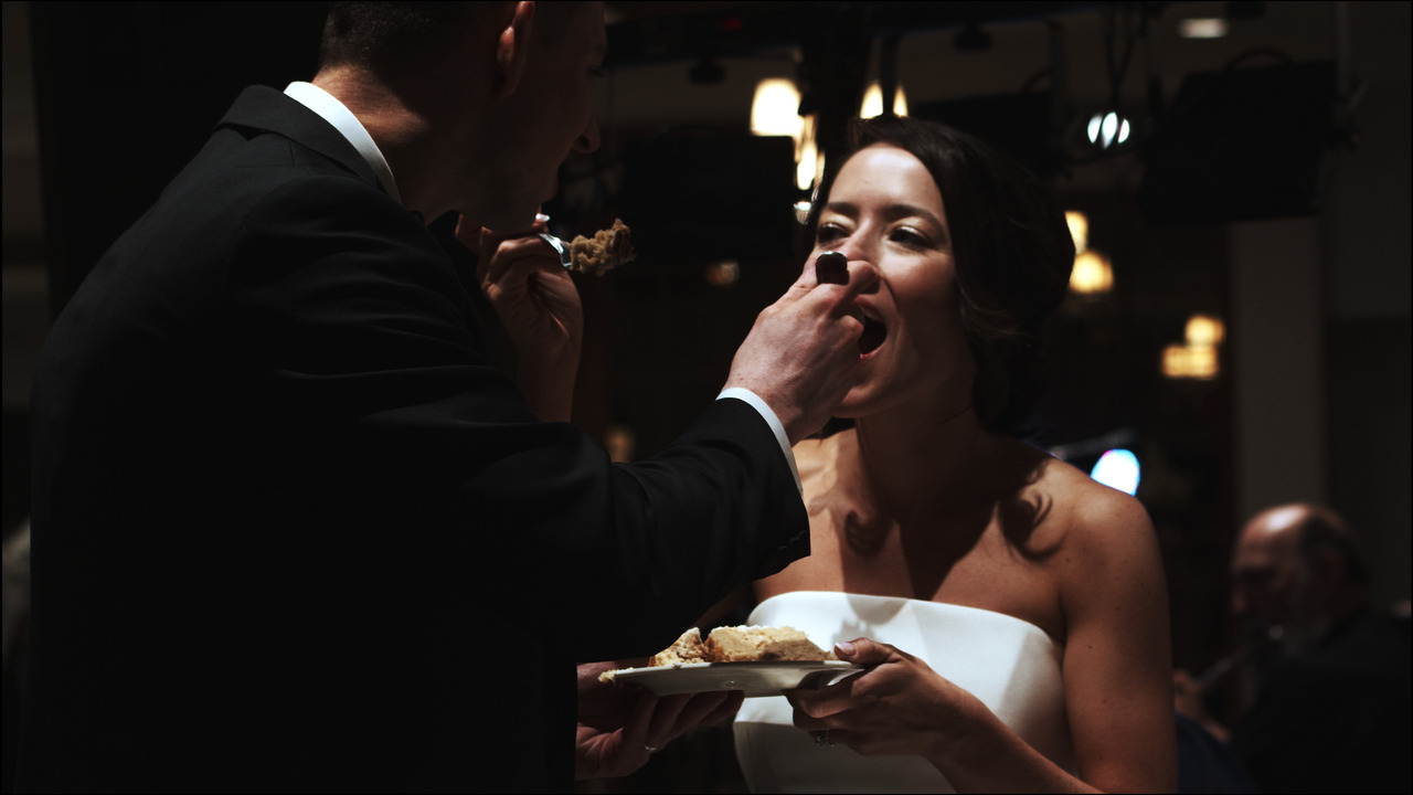 Bride and groom put forks of wedding cake in each others' mouths