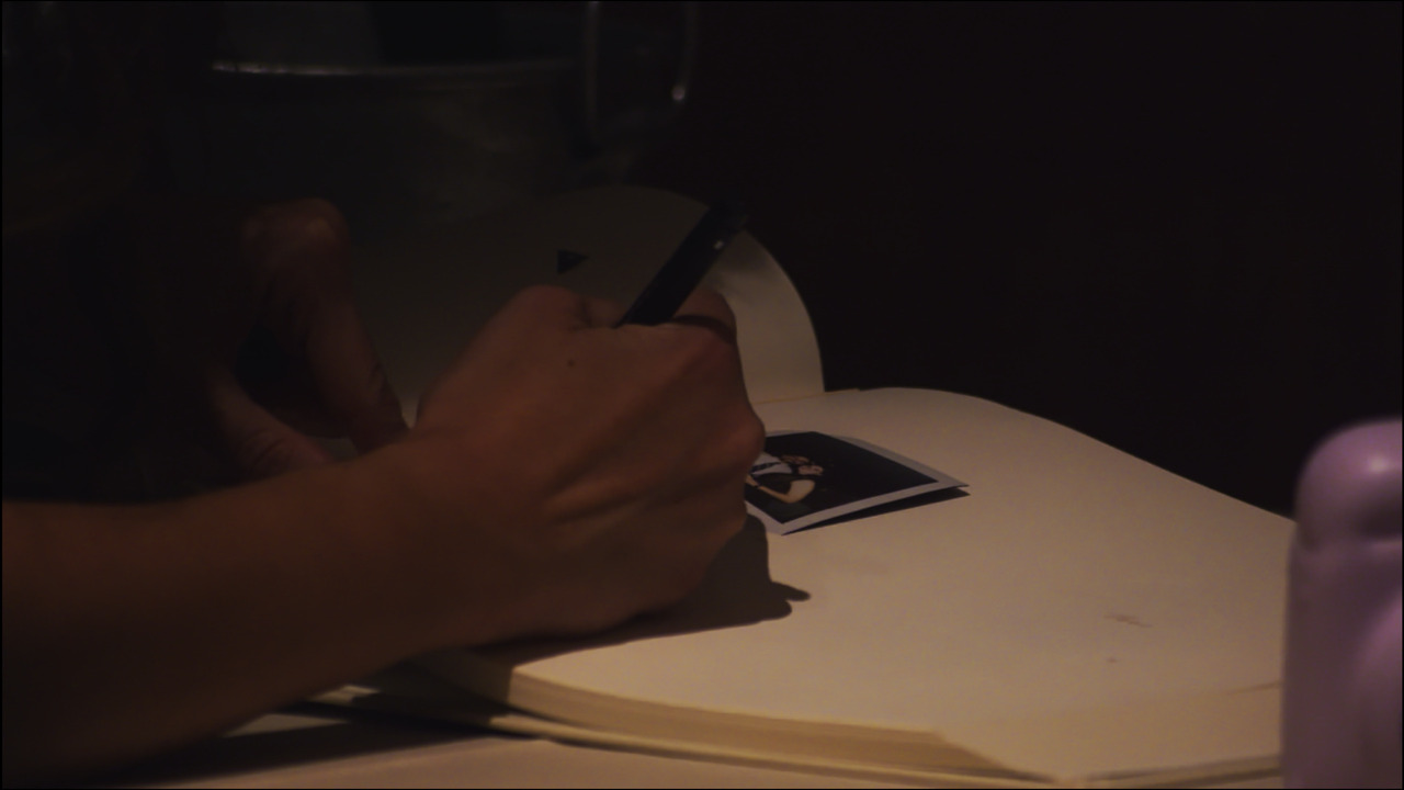 Closeup of guest's hand signing guestbook.