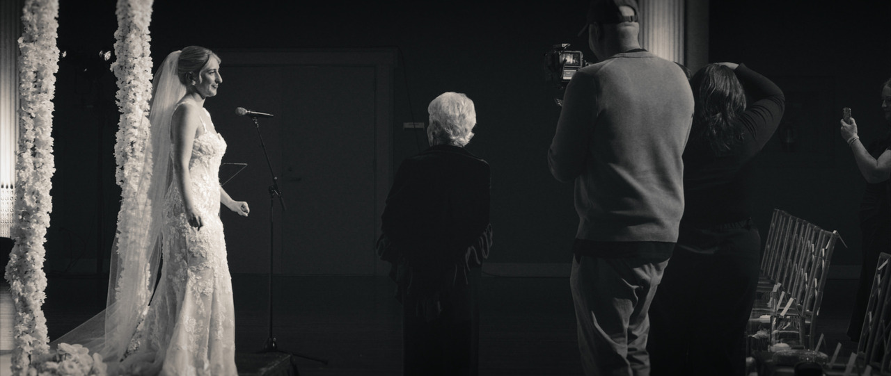 Bride standing at makeshift altar, dancing as guests walk in.
