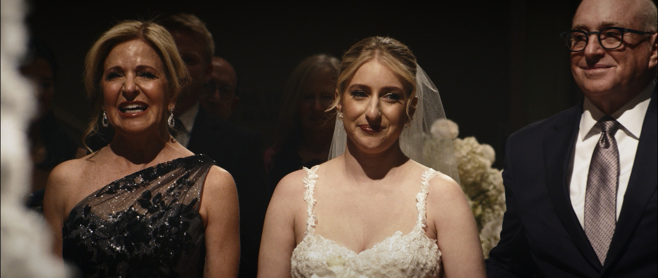 Bride walking down aisle with her parents.