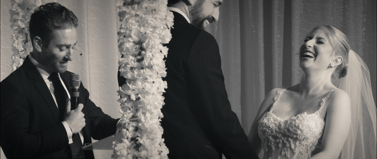 Bride and groom holding hands at alter, laughing.