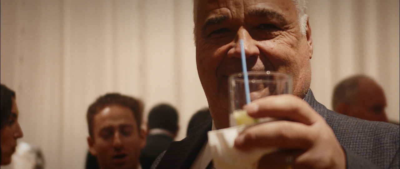 Elderly guest toasts camera.