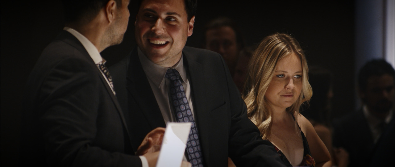 Two men and woman conversing at bar.