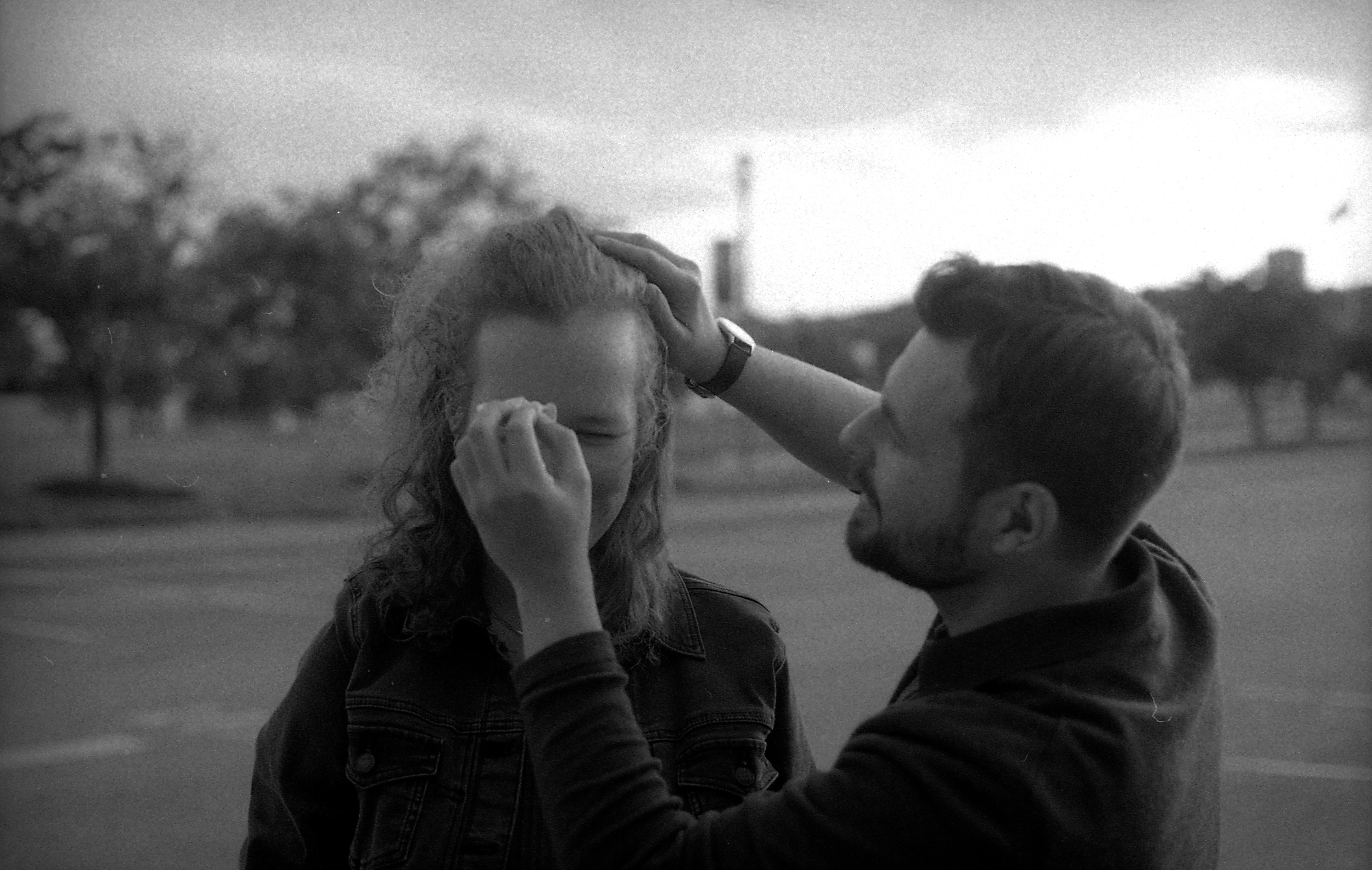 Man dabbing at his finace's face with cloth, black and white.
