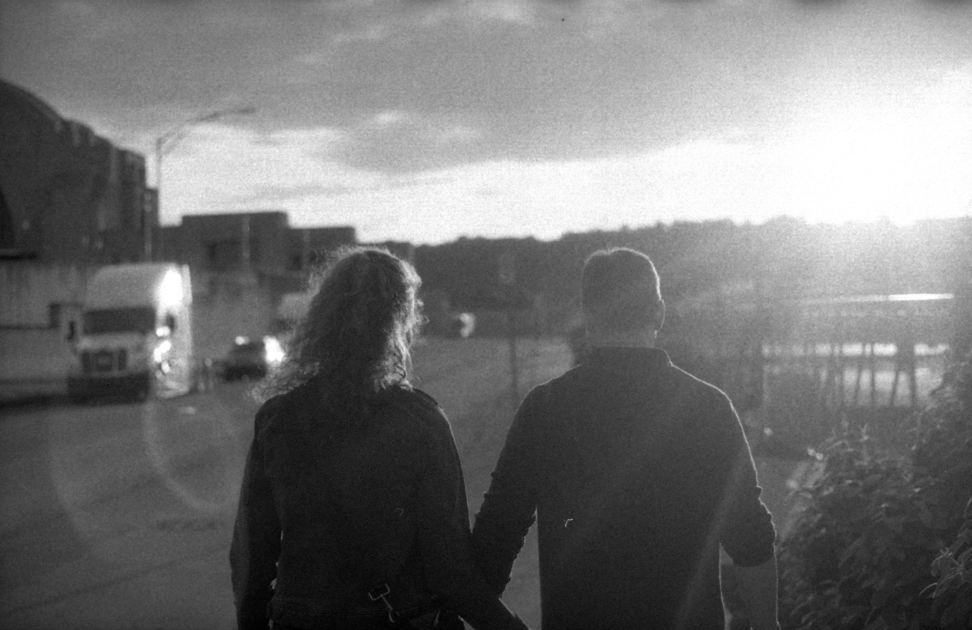 Couple walking down sidewalk, black and white.