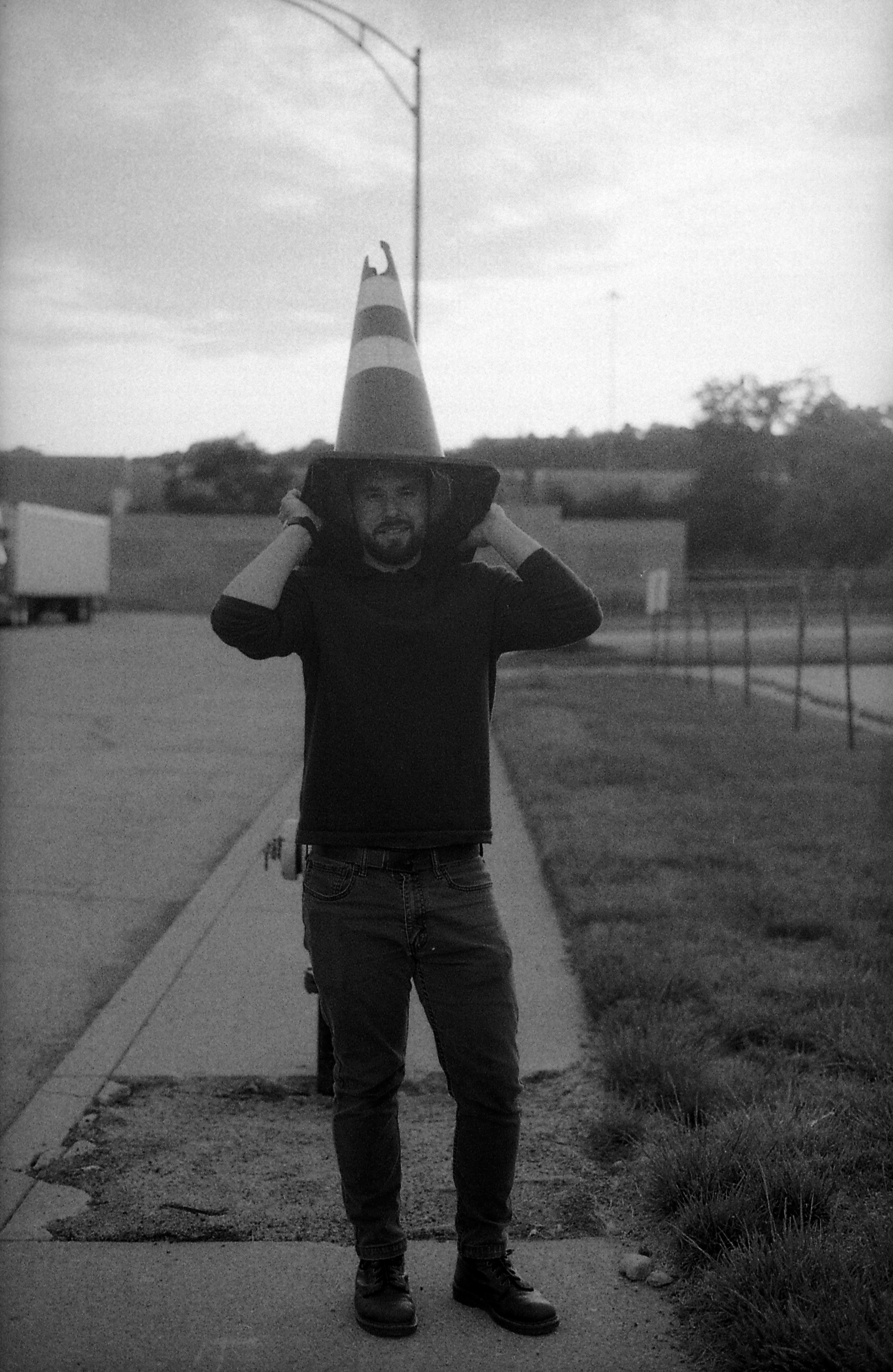 Man with traffic cone on head, black and white.